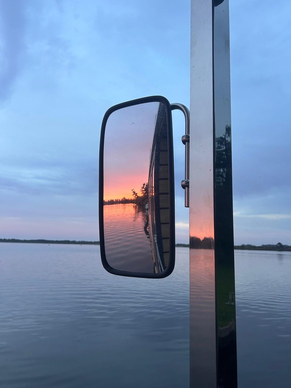 Seitenspiegel des Hausboots, darin der Sonnenuntergang