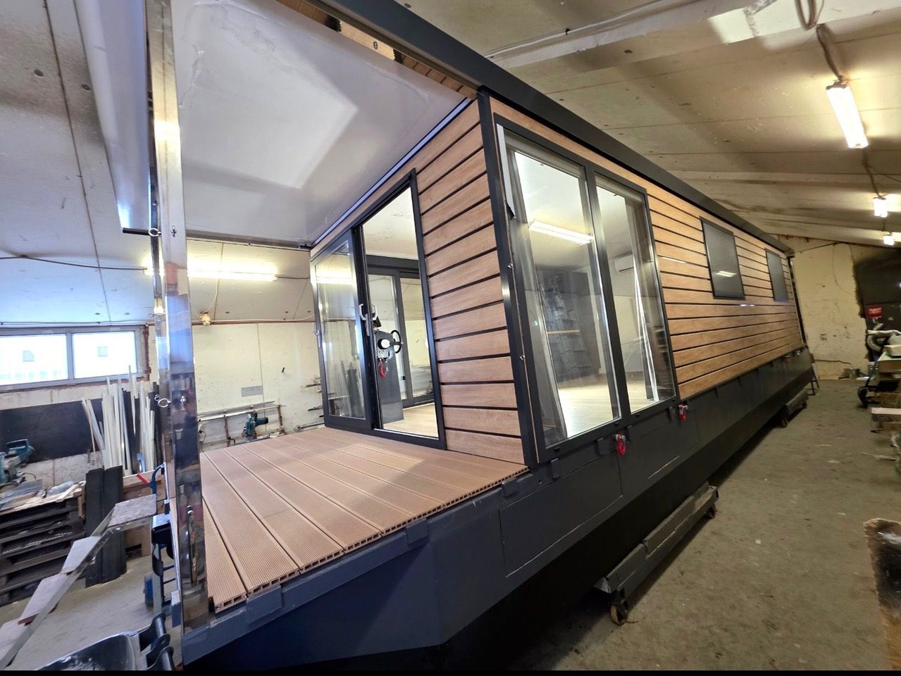 Hausboot im Bau in einer Halle, Fassade aus Holz, große Glastüren
