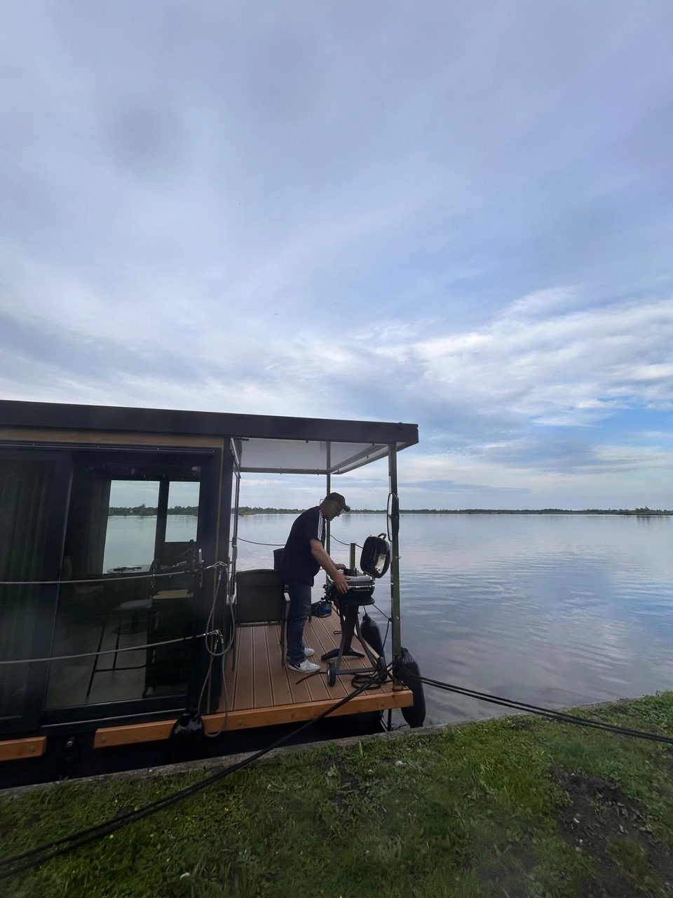 Hausboot am Ufer, dahinter weites Wasser